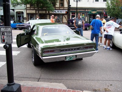 1972 Ford Ranchero - A green 1969 Dodge Coronet is displayed with its doors open, surrounded by onlookers at an outdoor event.