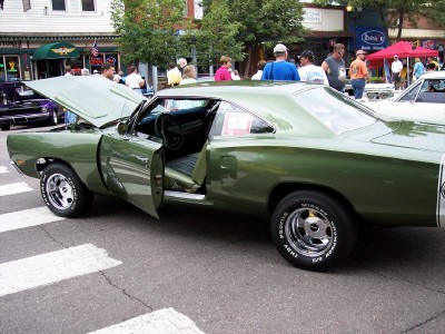 1972 Ford Ranchero - A green 1970s muscle car is displayed with its hood and driver's door open on a street.