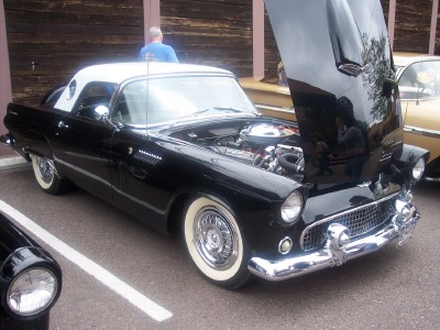 1972 Ford Ranchero - Black 1955 Ford Thunderbird with a white roof and hood open, parked next to another car.