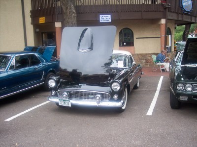 1972 Ford Ranchero - A black 1955 Ford Thunderbird is parked with its hood open, alongside other classic vehicles.