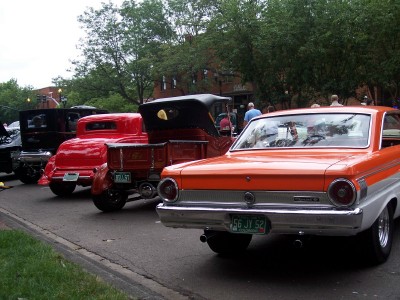1972 Ford Ranchero - A row of vintage vehicles are lined up on a street, with an orange and white coupe in the foreground.