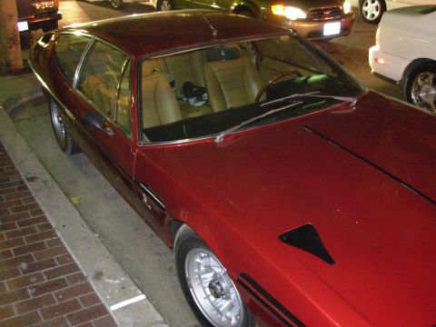 1995 Ford Taurus - A red coupe with a tan interior is parked on a street next to other vehicles.