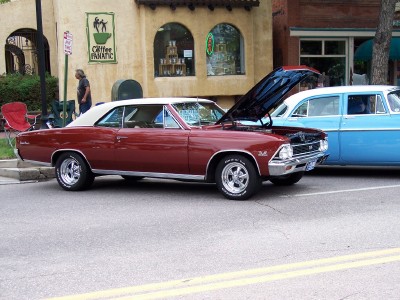 1972 Ford Ranchero - A maroon 1967 Chevrolet Chevelle SS coupe is parked on a street with its hood open, next to a blue sedan.