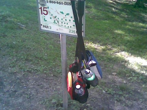 1997 Ford Probe - Disc golf bags are hung on a signpost at a disc golf course.