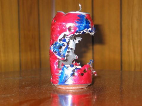 2004 Ford F-150 - This crushed soda can is heavily damaged with large holes torn in its side.