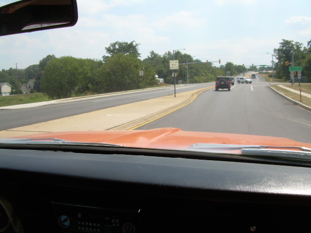 Driver's view over orange dash and black pad onto a divided road with a Jeep ahead