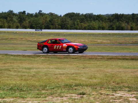2001 Mercury Grand Marquis - A red race car numbered 611 drives on a track during a sunny day.