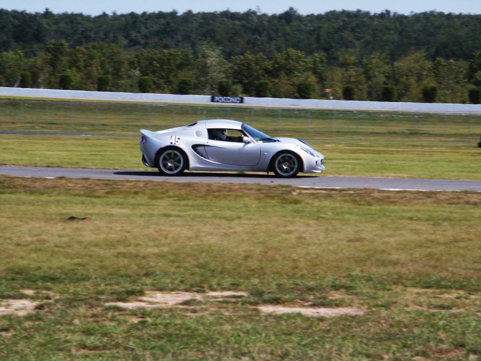 Silver Lotus Elise sports car with number 45 on the door, driving on a race track