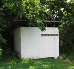 1997 Ford Probe - An old outhouse sits surrounded by trees, with a sign identifying it as Brown's Outhouse.