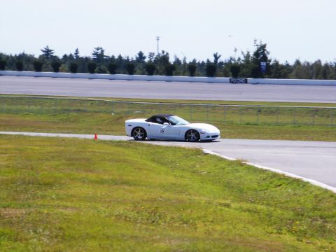 2001 Mercury Grand Marquis - A white convertible sports car navigates a turn on a race track under a clear sky.