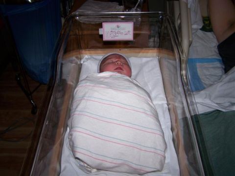1995 Ford Bronco - A baby sleeps soundly in a hospital bassinet, swaddled in a blanket with pink and blue stripes.