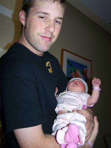 1995 Ford Bronco - A man holds a newborn baby, who is dressed in white and pink clothing.