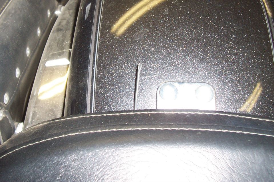 Close-up of a motorcycle's black speckled fender and stitched seat