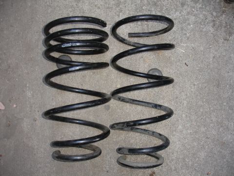 1995 Ford Taurus - A set of two automotive coil springs are shown resting on a concrete floor.