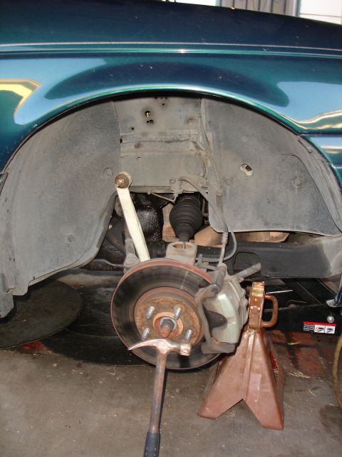 1995 Ford Taurus - Close-up of the front suspension and brake system of a green 1995 Ford Taurus.