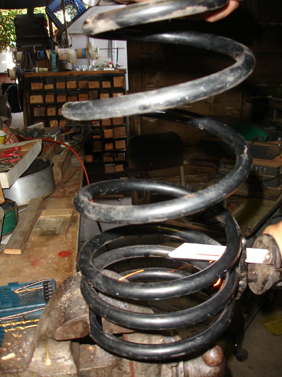 Black coil spring held in a vise