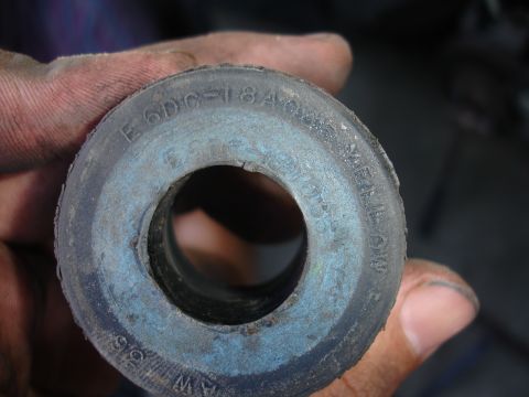 1995 Ford Taurus - A hand holds a used rubber bushing with visible part numbers and size indicators.