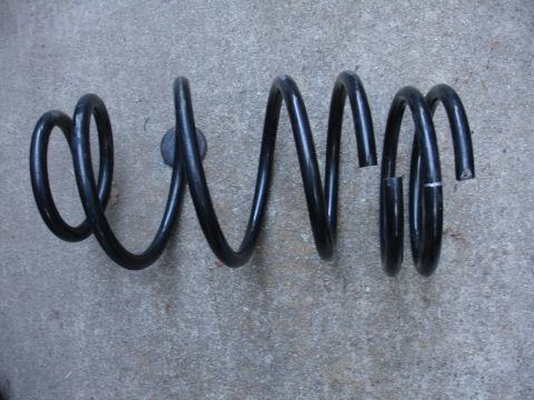 1995 Ford Taurus - A black coil spring, likely for a vehicle suspension, is shown with a visible break in one of its coils.