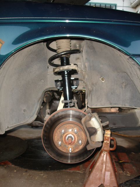 1995 Ford Taurus - Close-up of a car's front suspension and brake system, showing the shock absorber and rotor.