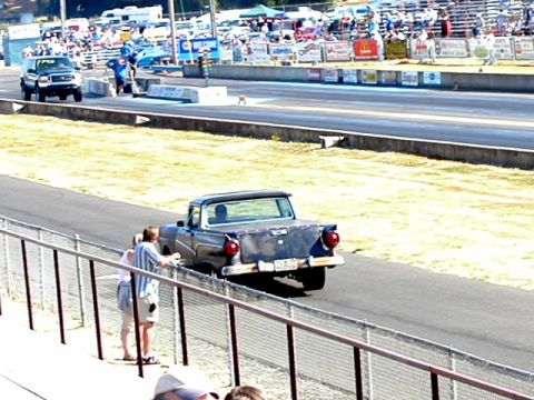 1967 Ford Ranchero - A classic Ford pickup truck is viewed from behind at a drag racing event with spectators in the background.