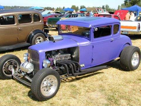 1967 Ford Ranchero - A custom purple coupe with a prominent V8 engine sits on display at an outdoor car show.