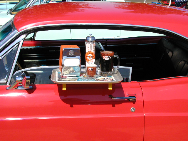 red car door with a tray holding A&W root beer mugs and a napkin dispenser