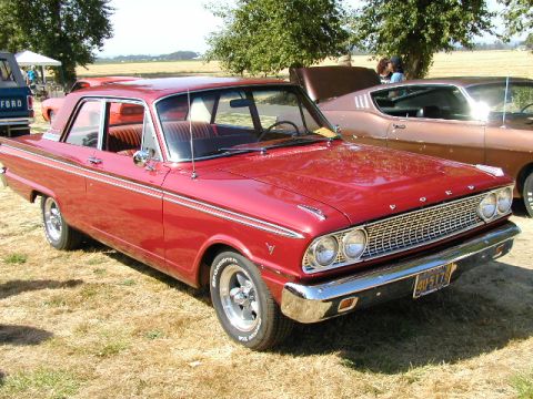 1967 Ford Ranchero - A red 1962 Ford Fairlane is parked outside with a brown car behind it.