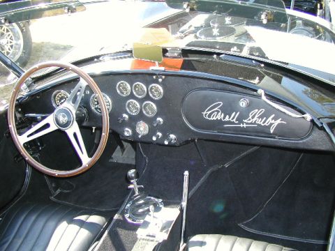 1967 Ford Ranchero - The interior of a Shelby Cobra features a wood-rimmed steering wheel and a dashboard with multiple gauges and Carroll Shelby's signature.