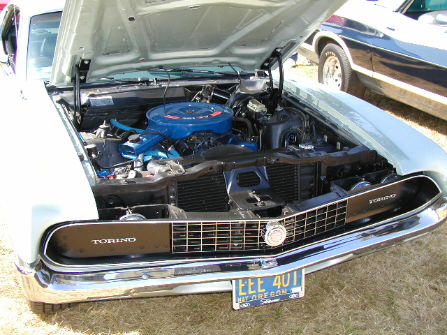Light blue Ford Torino with hood open, showing engine. Another car is visible behind it