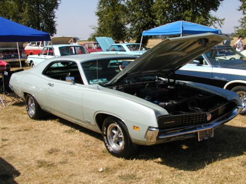 1967 Ford Ranchero - A light blue 1970 Ford Torino GT is displayed with its hood open at an outdoor car show.
