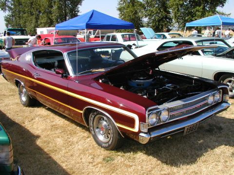 1967 Ford Ranchero - A maroon 1969 Ford Torino GT is displayed with its hood open at a car show.
