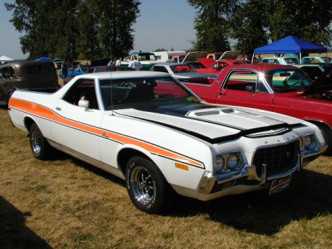 1967 Ford Ranchero - A white 1972 Ford Ranchero with orange racing stripes is displayed at an outdoor car show, with other vehicles visible.