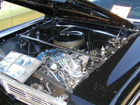 1967 Ford Ranchero - The engine bay of a black 1967 Ford Ranchero is displayed, a chrome air cleaner and blue spark plug wires.