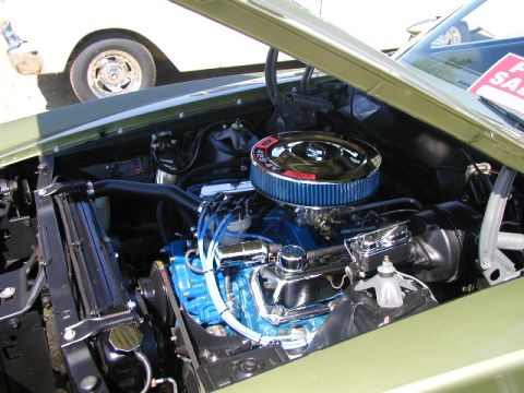 1967 Ford Ranchero - Engine bay of a 1967 Ford Ranchero, a blue engine and chrome air cleaner, with another vehicle visible in the background.