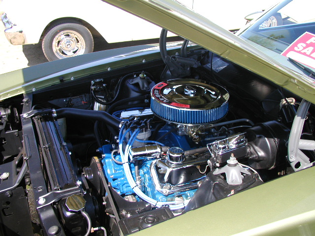 1967 Ford Ranchero engine bay with blue engine block, chrome air cleaner, and "For Sale" sign