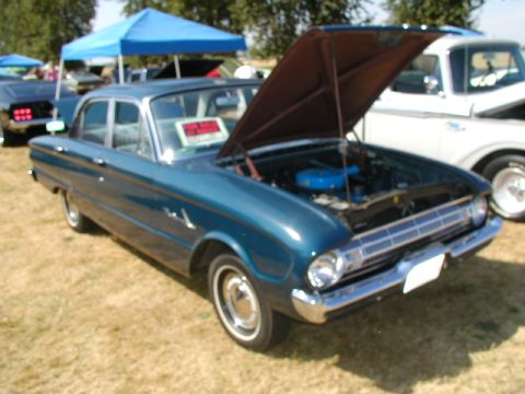 1967 Ford Ranchero - A blue sedan, likely from the early 1960s, is displayed with its hood open at an outdoor car show.