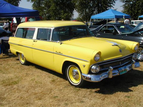1967 Ford Ranchero - A yellow station wagon is parked on grass under a blue tent at an outdoor event.