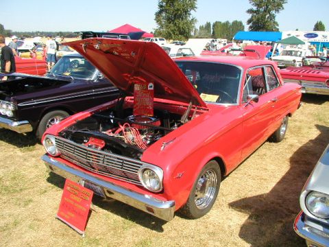 1967 Ford Ranchero - Red 1963 Ford Falcon Futura at a car show, hood open, with a club sign in front.