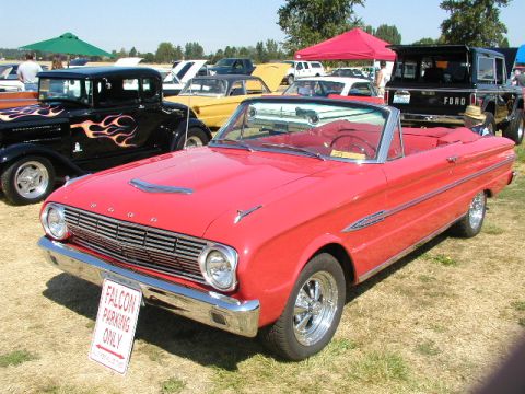 1967 Ford Ranchero - A red convertible, possibly a 1963 Ford Falcon, parked at an outdoor event with other vehicles.