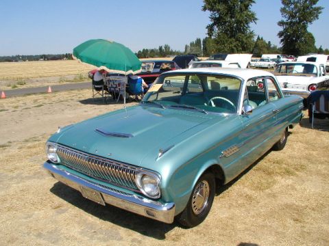 1967 Ford Ranchero - A teal and white Ford Falcon is parked at an outdoor event with other vehicles in the background.