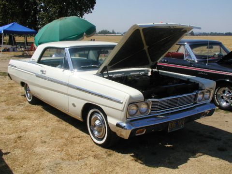 1967 Ford Ranchero - A white 1965 coupe is displayed with its hood open, parked next to another vehicle at an outdoor event.