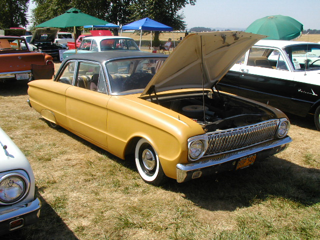 Yellow sedan with hood open, showing engine. Whitewall tires, chrome grille. Parked on grass