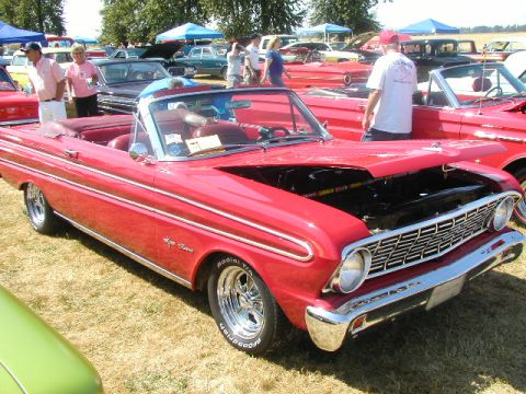 1967 Ford Ranchero - Red convertible classic car at an outdoor car show, hood open, with other vehicles in the background.