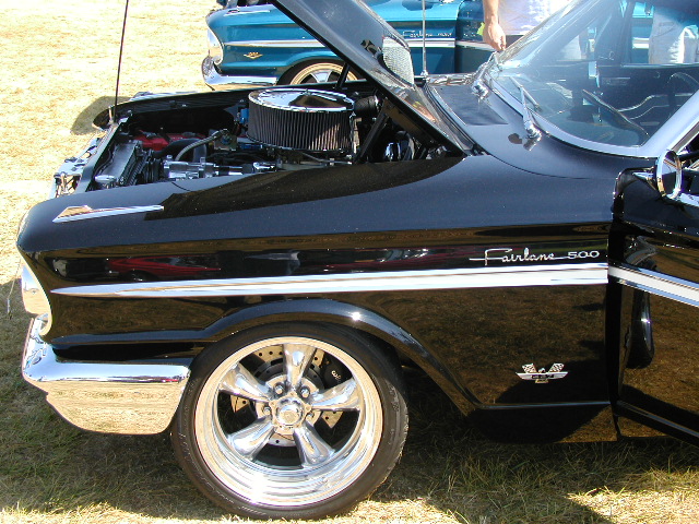 Black 1960 Ford Fairlane 500 with chrome trim and custom wheels, engine visible