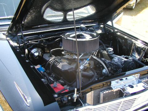 1967 Ford Ranchero - The engine compartment of a classic car is shown with the hood open, revealing the V8 engine and its components.