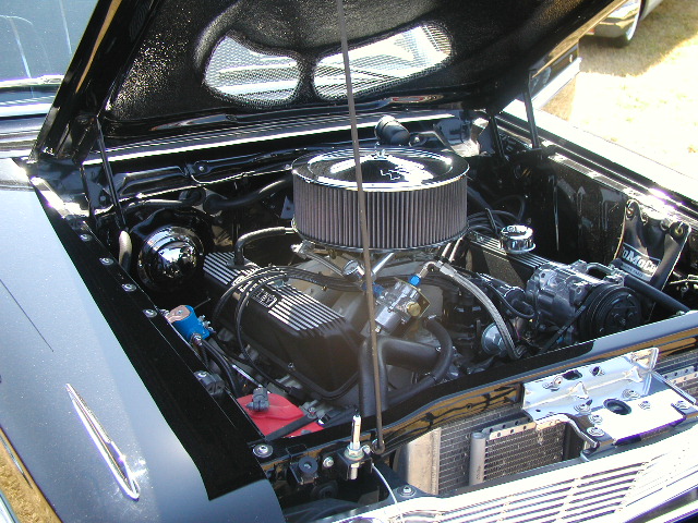 Close-up of a black engine bay with chrome air cleaner and V8 engine. Some text is visible on the valve cover