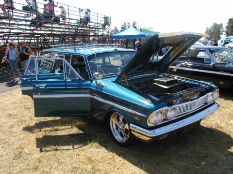 1967 Ford Ranchero - A teal 1962 Ford Falcon Squire wagon is displayed with its hood and driver's door open at a car show.