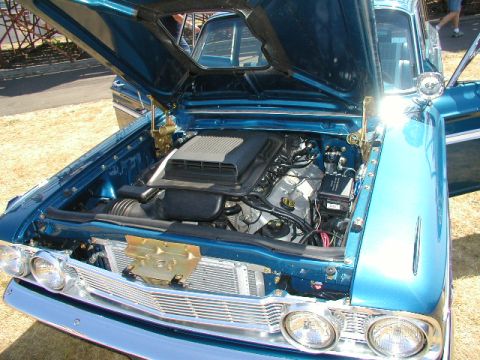 1967 Ford Ranchero - The engine bay of a classic blue car is displayed with the hood open, revealing the motor and air intake.
