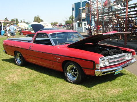 1967 Ford Ranchero - A red pickup truck is parked on a grassy field with its hood open, displaying its engine.