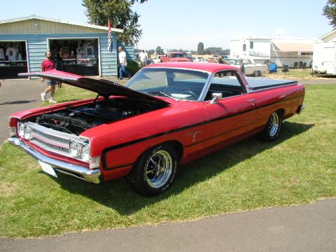 1967 Ford Ranchero - A red pickup truck is parked on grass with its hood up, displaying the engine bay.